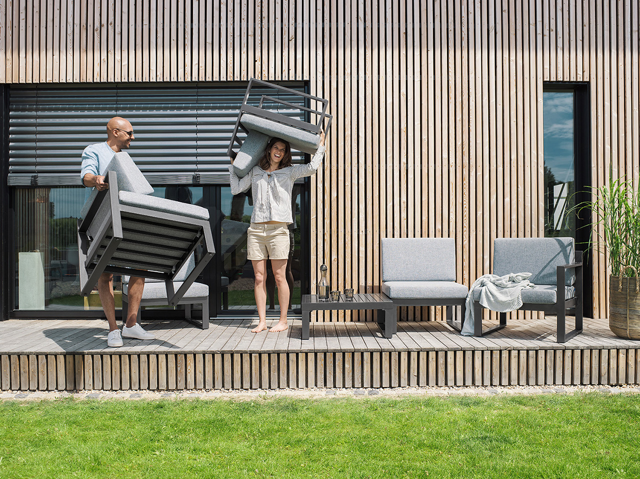 Mann und Frau tragen Sofa durch den Garten