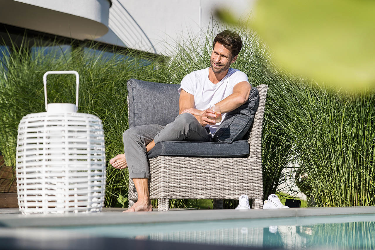 Männliches Model sitzt in einem Sessel auf der Terrasse