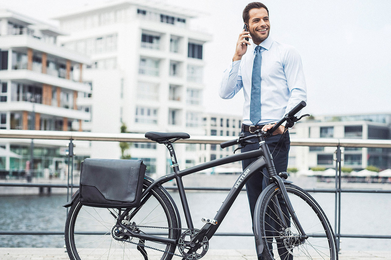 Männliches Model steht draussen am Fahrrad und telefoniert